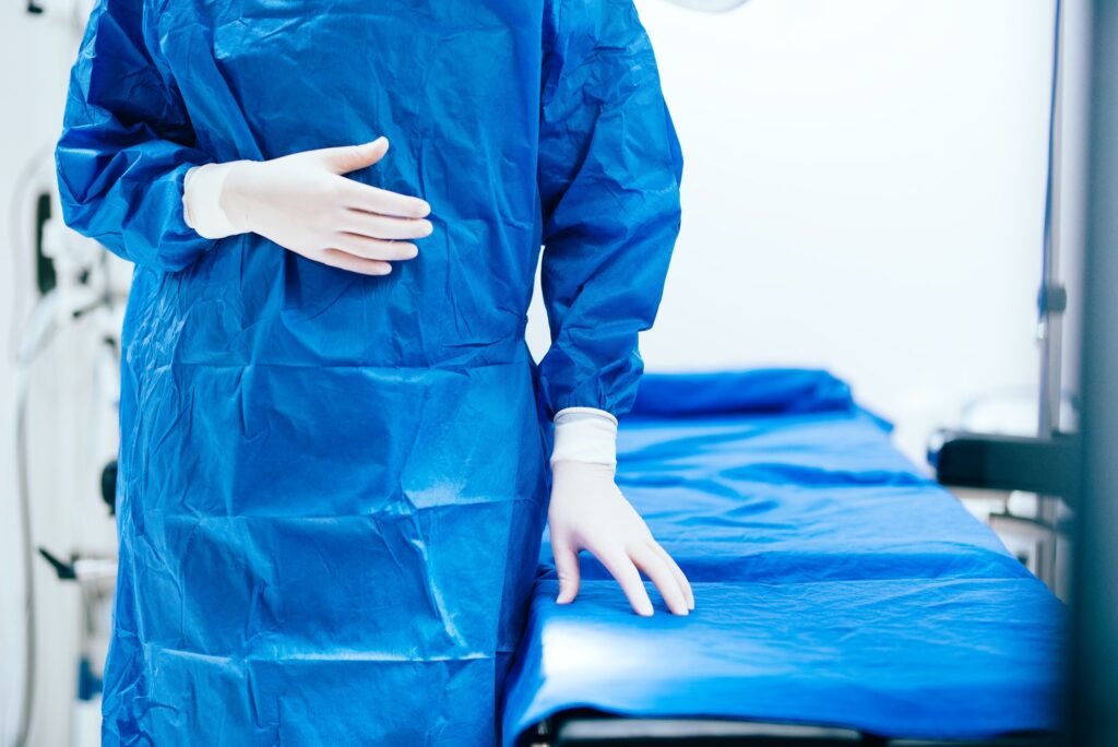 Details of surgeon scrubs, rubber gloves and operating table. Portrait of surgeon