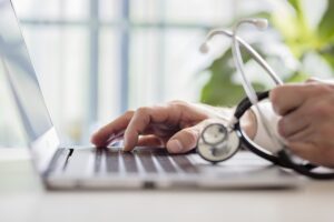 Doctor entering patient notes on laptop in surgery