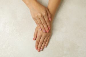 Female hands with pink nails on white background, top view